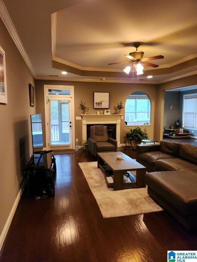 living room with crown molding, ceiling fan, and dark wood-type flooring