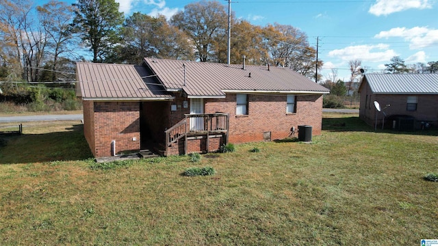 back of property with central AC unit and a lawn