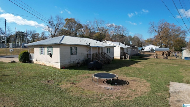 view of side of home with a trampoline and a yard