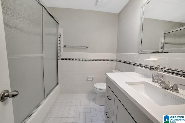 full bathroom featuring vanity, tile patterned flooring, toilet, enclosed tub / shower combo, and tile walls