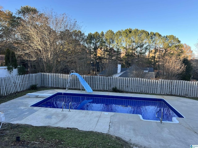 view of pool featuring a diving board, a water slide, and a patio