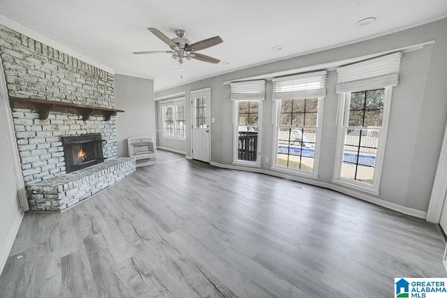 unfurnished living room featuring ceiling fan, wood-type flooring, and a brick fireplace