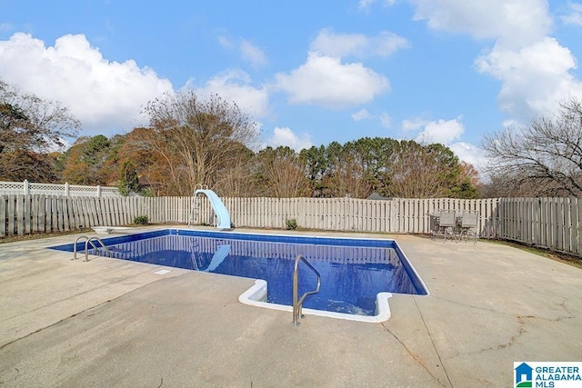 view of swimming pool featuring a diving board, a patio area, and a water slide