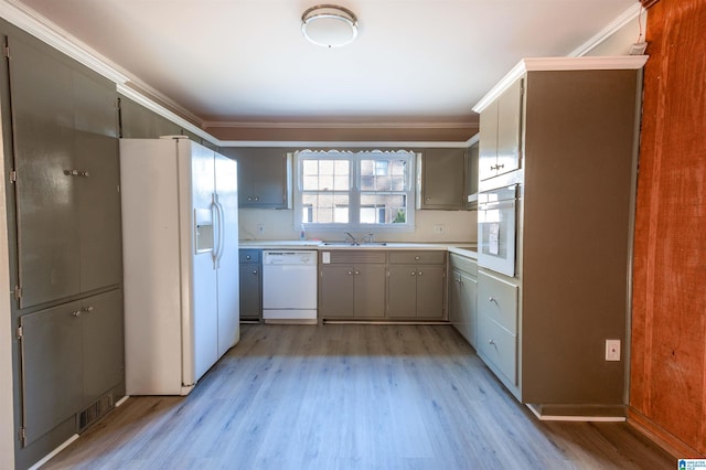 kitchen with crown molding, light wood-type flooring, white appliances, and sink