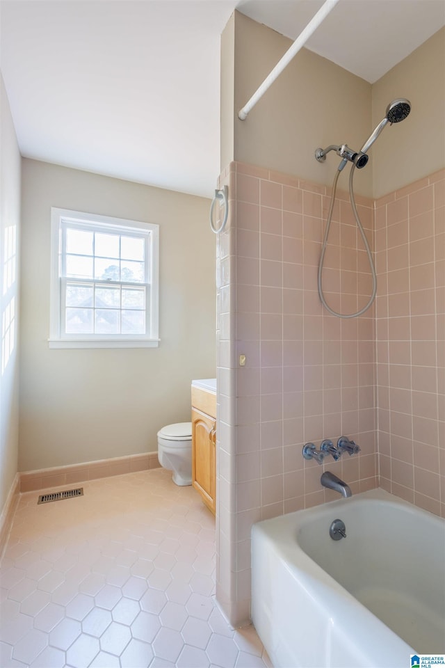 full bathroom featuring tile patterned floors, vanity, tiled shower / bath combo, and toilet