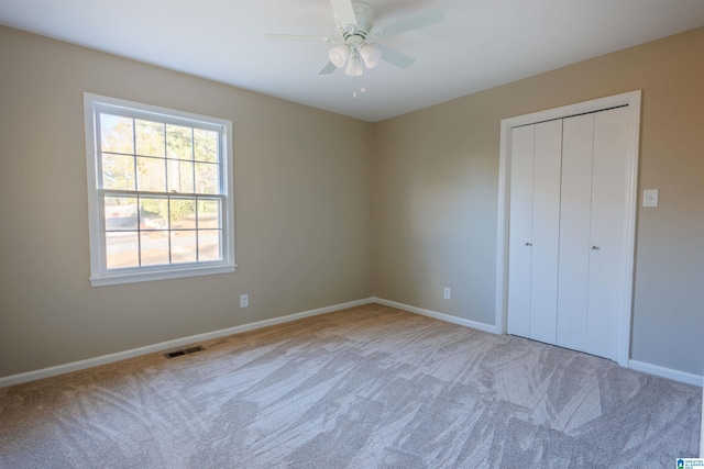 unfurnished bedroom featuring ceiling fan, a closet, and light carpet