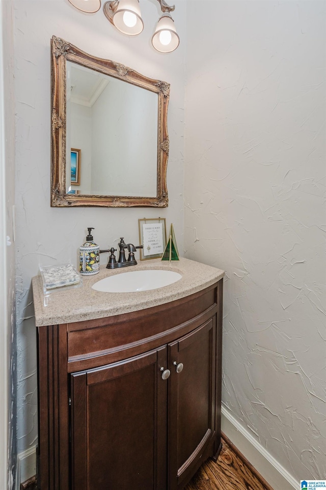 bathroom with hardwood / wood-style floors, vanity, and crown molding