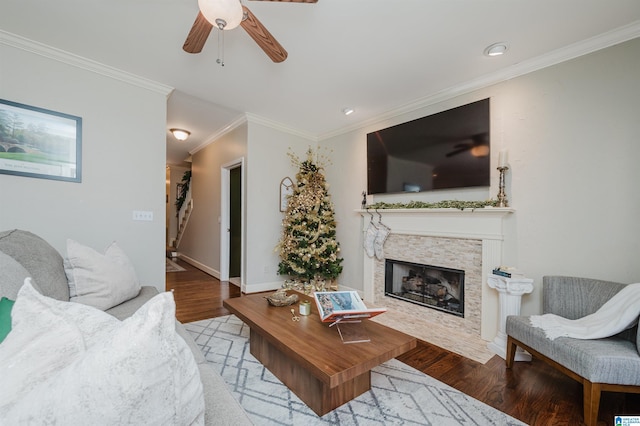 living room with light hardwood / wood-style floors, a stone fireplace, and crown molding