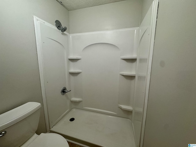 bathroom featuring a shower, a textured ceiling, and toilet