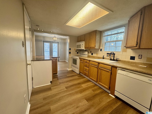 kitchen with french doors, tasteful backsplash, white appliances, sink, and light hardwood / wood-style flooring