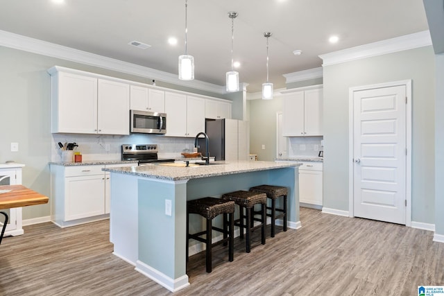 kitchen featuring appliances with stainless steel finishes, light wood-type flooring, a center island with sink, and white cabinetry