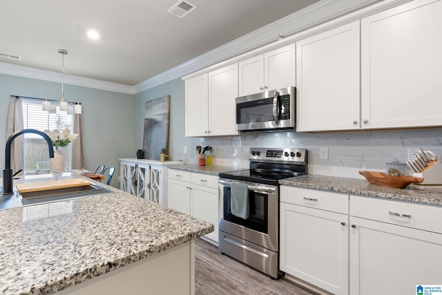 kitchen featuring white cabinetry, sink, crown molding, decorative light fixtures, and appliances with stainless steel finishes