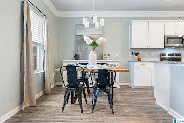 dining area with light hardwood / wood-style flooring, ornamental molding, and an inviting chandelier