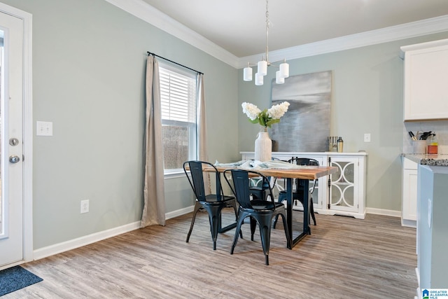 dining area with an inviting chandelier, light hardwood / wood-style flooring, and crown molding