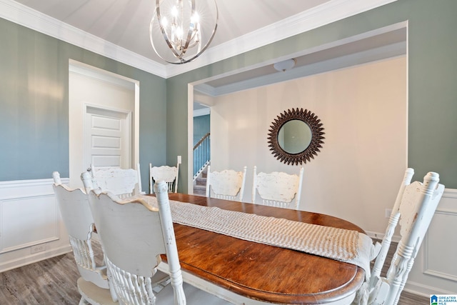 dining area with hardwood / wood-style flooring, a notable chandelier, and ornamental molding