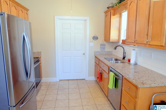 kitchen featuring light stone countertops, sink, decorative backsplash, light tile patterned flooring, and appliances with stainless steel finishes