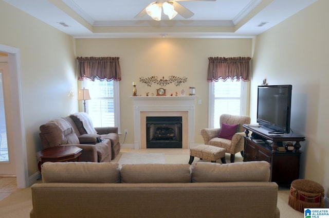 tiled living room with a raised ceiling, ceiling fan, and ornamental molding