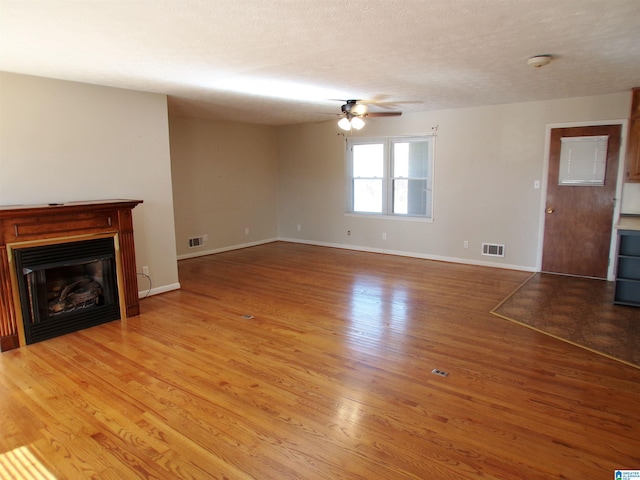 unfurnished living room with ceiling fan, hardwood / wood-style floors, and a textured ceiling