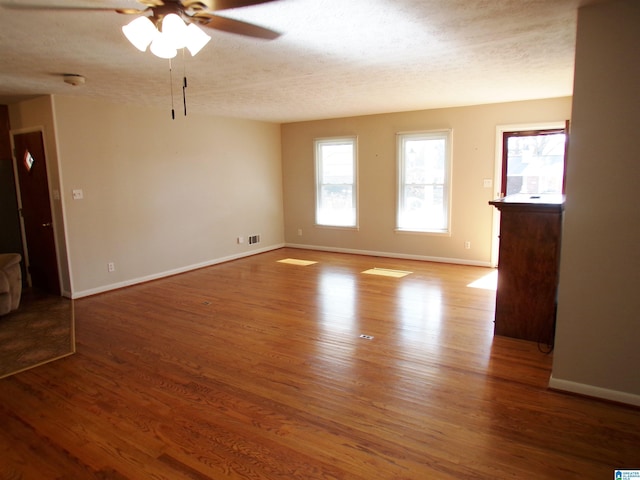 unfurnished living room with ceiling fan, a textured ceiling, and hardwood / wood-style flooring