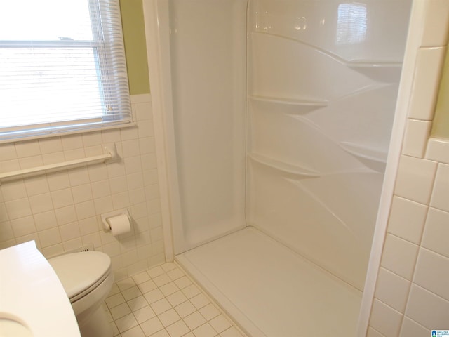 bathroom with toilet, tile patterned floors, walk in shower, and tile walls