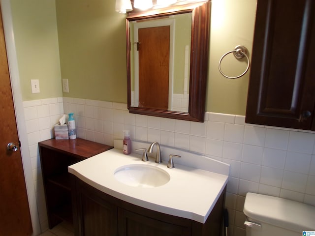 bathroom with vanity, toilet, and tile walls