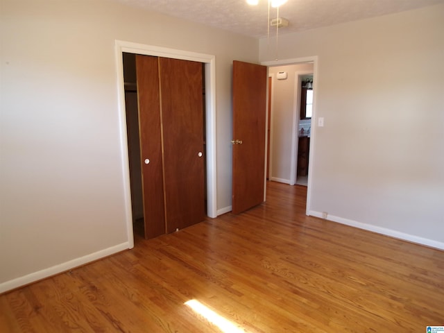 unfurnished bedroom with light hardwood / wood-style floors, a textured ceiling, and a closet