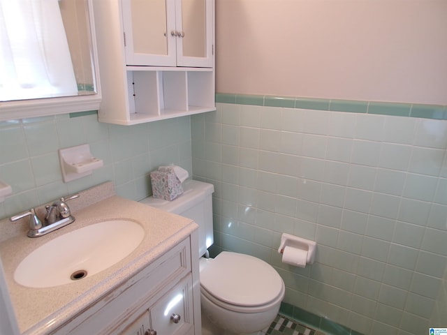 bathroom featuring vanity, tile walls, and toilet