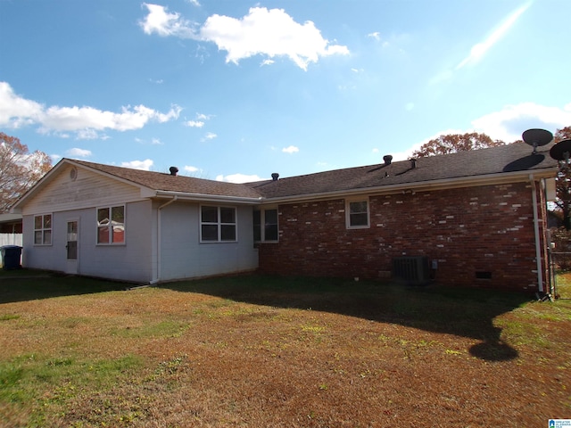 rear view of house with central AC unit and a yard