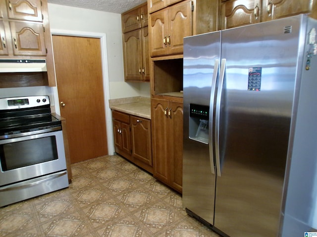 kitchen featuring a textured ceiling, stainless steel appliances, and range hood