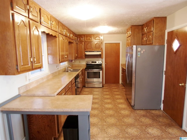 kitchen with kitchen peninsula, sink, a textured ceiling, and appliances with stainless steel finishes