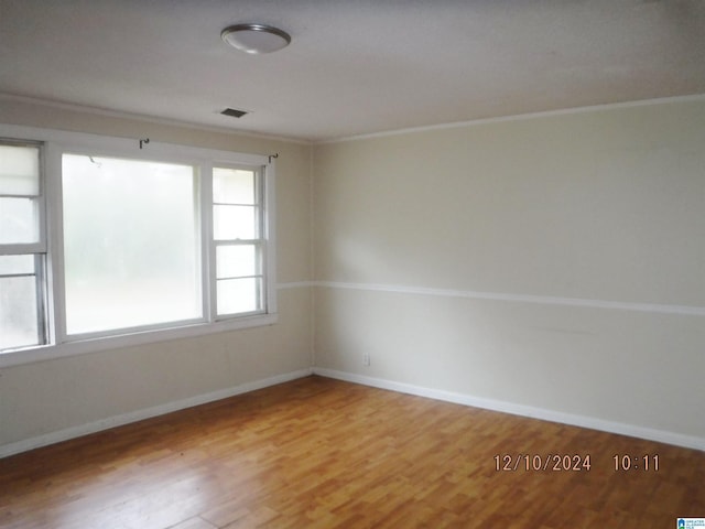 empty room featuring wood-type flooring and crown molding