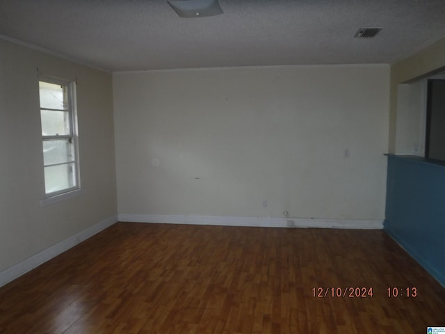 spare room with a textured ceiling, dark hardwood / wood-style floors, and ornamental molding