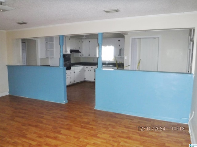 kitchen featuring white cabinetry, hardwood / wood-style floors, a textured ceiling, and ornamental molding