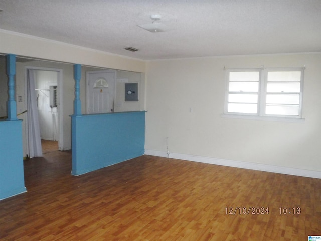 empty room featuring hardwood / wood-style floors, crown molding, a textured ceiling, and electric panel