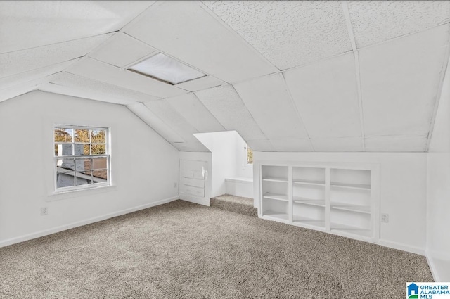 additional living space featuring built in shelves, carpet floors, and vaulted ceiling