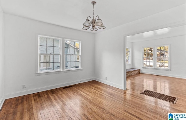 unfurnished dining area featuring a chandelier and hardwood / wood-style flooring