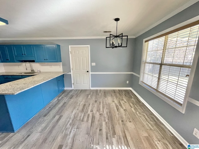 kitchen with ornamental molding, blue cabinets, pendant lighting, light hardwood / wood-style flooring, and a notable chandelier