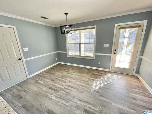 unfurnished dining area featuring hardwood / wood-style flooring, a notable chandelier, and ornamental molding