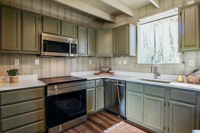 kitchen featuring appliances with stainless steel finishes, dark hardwood / wood-style floors, beam ceiling, and sink