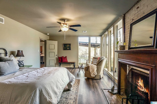 bedroom featuring ceiling fan, dark wood-type flooring, and a brick fireplace