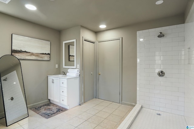 bathroom with tile patterned flooring, vanity, and tiled shower