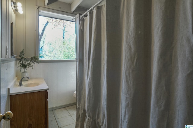 bathroom with tile patterned flooring, vanity, toilet, and tile walls