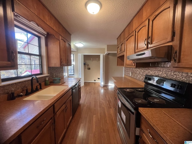 kitchen with light hardwood / wood-style floors, sink, stainless steel appliances, and tasteful backsplash