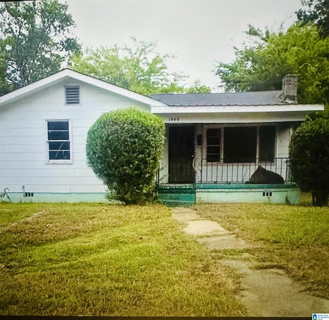 back of property with a yard and a porch