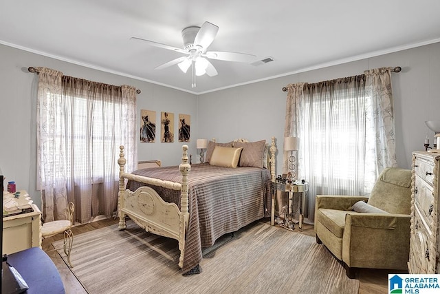 bedroom featuring ceiling fan, light hardwood / wood-style floors, crown molding, and multiple windows