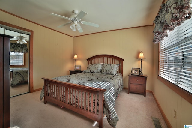 bedroom featuring ceiling fan, crown molding, light carpet, and a closet