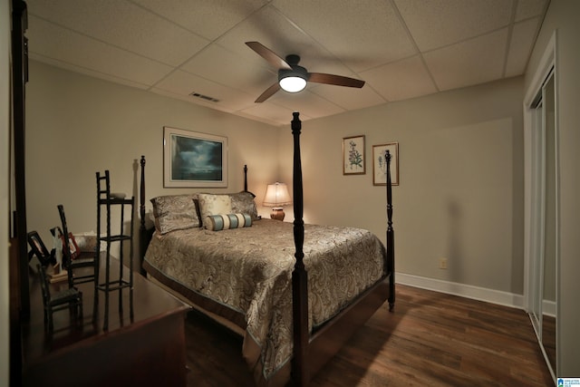 bedroom featuring ceiling fan, a drop ceiling, and dark hardwood / wood-style flooring