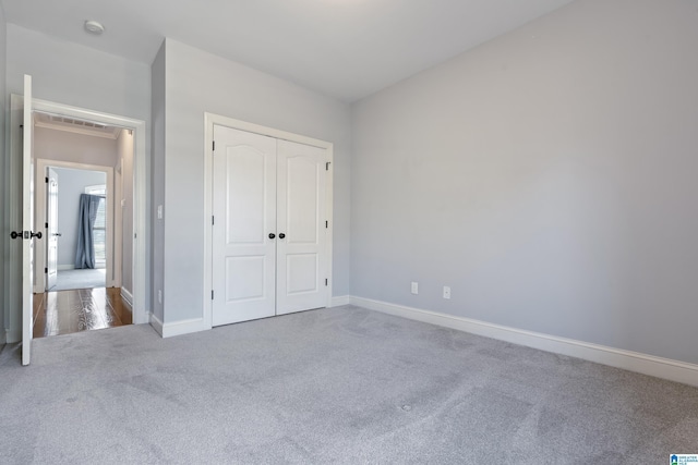 unfurnished bedroom with light colored carpet and a closet