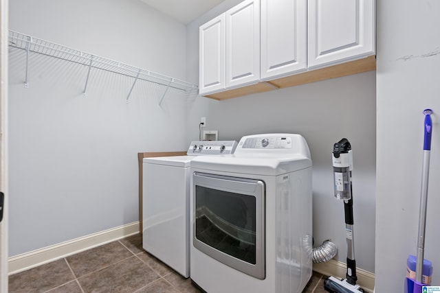 laundry room featuring washing machine and dryer, cabinets, and dark tile patterned flooring