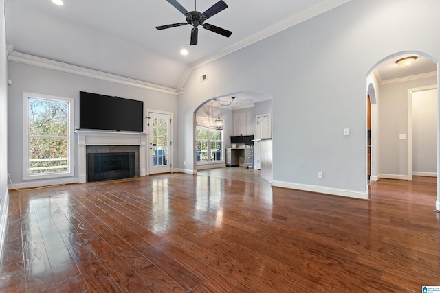 unfurnished living room with ceiling fan with notable chandelier, dark hardwood / wood-style flooring, a wealth of natural light, and crown molding